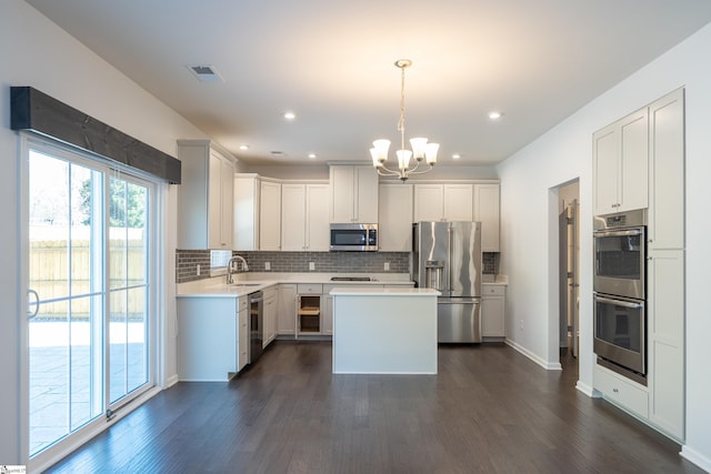 kitchen with stainless steel appliances, dark wood-type flooring, backsplash, and light countertops