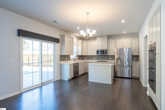 kitchen with a sink, visible vents, light countertops, appliances with stainless steel finishes, and dark wood-style floors