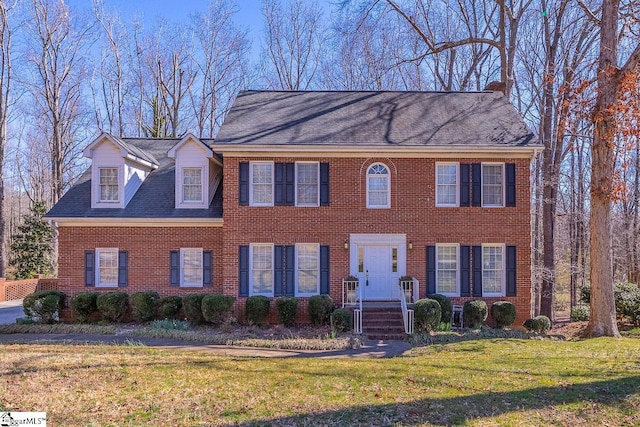 view of front facade with roof with shingles, brick siding, and a front lawn