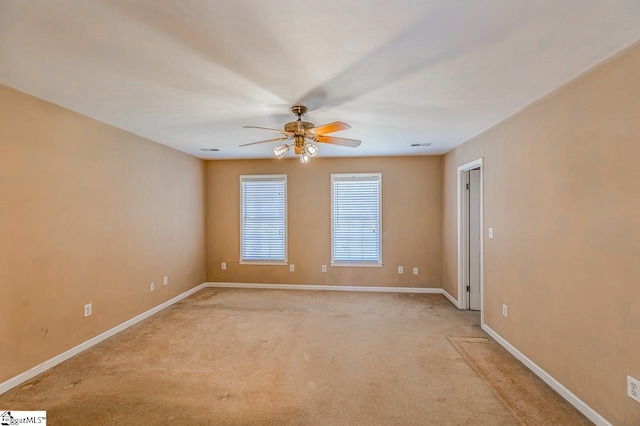 spare room with a ceiling fan, light colored carpet, and baseboards