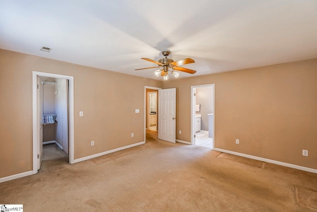 unfurnished bedroom featuring visible vents, light carpet, baseboards, and a spacious closet