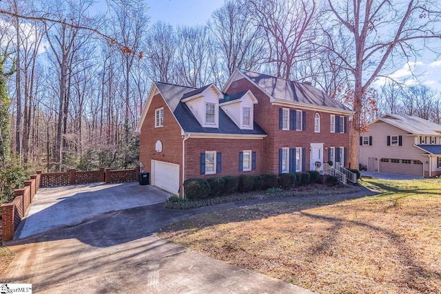 view of front of house featuring an attached garage, driveway, fence, and brick siding