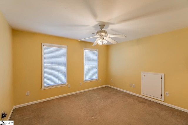 carpeted spare room with ceiling fan and baseboards