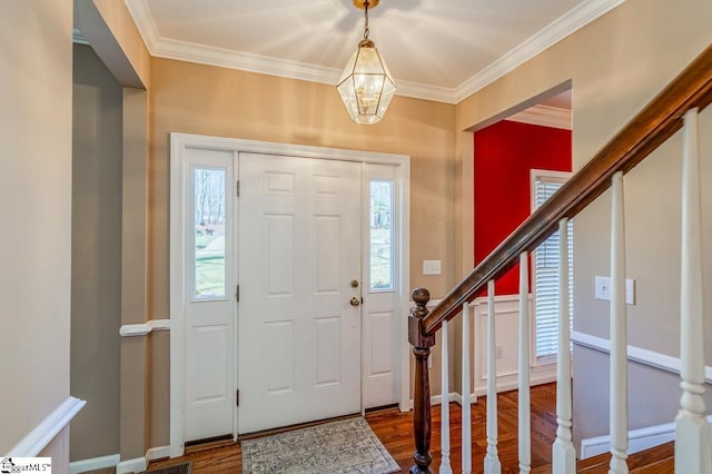 foyer entrance featuring a notable chandelier, stairway, crown molding, and wood finished floors