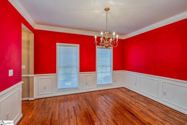 unfurnished dining area with wood finished floors, wainscoting, crown molding, and an inviting chandelier