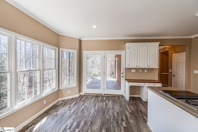 kitchen with dark wood-style floors, a healthy amount of sunlight, white cabinets, and ornamental molding