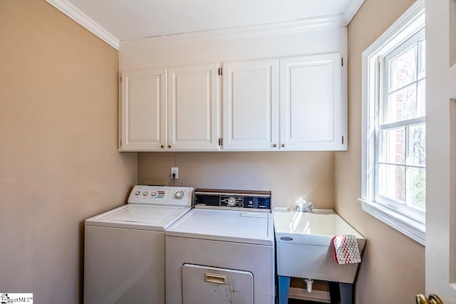 laundry area featuring ornamental molding, cabinet space, a sink, and washing machine and clothes dryer