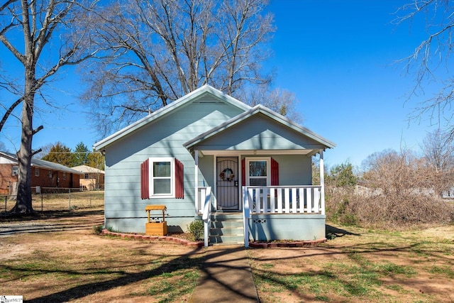 bungalow-style home with a front lawn, fence, and a porch