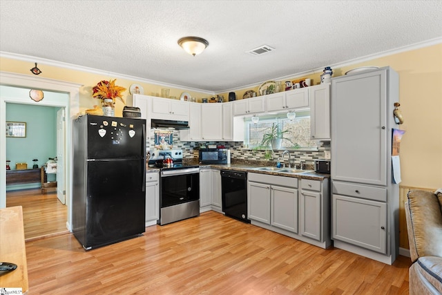 kitchen with a sink, visible vents, light wood-style floors, black appliances, and crown molding