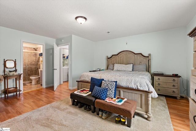 bedroom with light wood-type flooring, visible vents, a textured ceiling, and baseboards