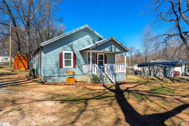 bungalow with a porch, a front yard, and cooling unit