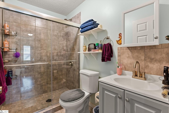 full bathroom with backsplash, toilet, vanity, a shower stall, and a textured ceiling