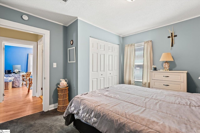 bedroom with baseboards, a textured ceiling, crown molding, carpet flooring, and a closet