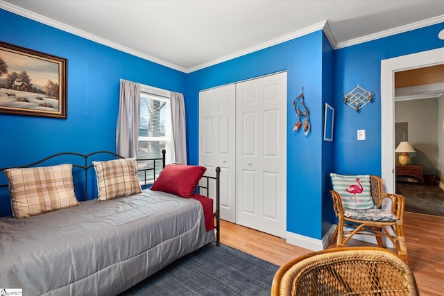 bedroom with crown molding, a closet, baseboards, and wood finished floors