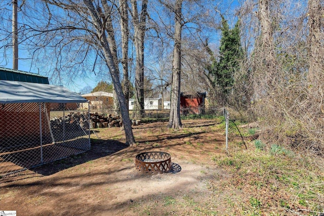 view of yard featuring an outdoor fire pit, fence, and an outdoor structure