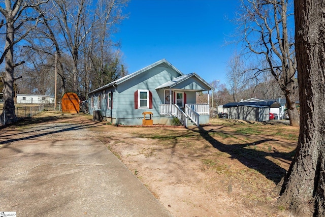 bungalow-style home featuring an outbuilding, a storage unit, fence, a porch, and a front yard