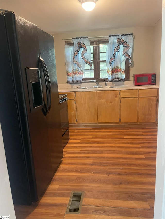 kitchen with light countertops, visible vents, a sink, and black appliances