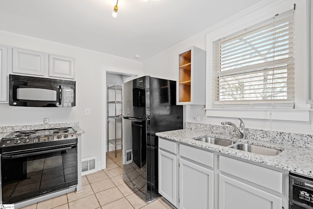 kitchen featuring light tile patterned floors, white cabinets, crown molding, black appliances, and a sink