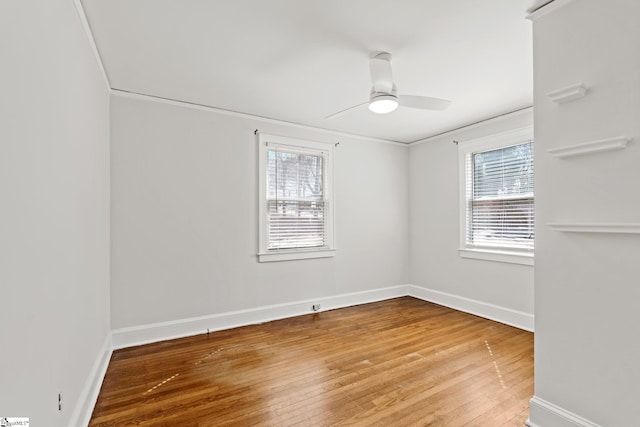 spare room featuring a healthy amount of sunlight, hardwood / wood-style flooring, and baseboards