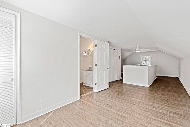 additional living space with baseboards, vaulted ceiling, and light wood finished floors