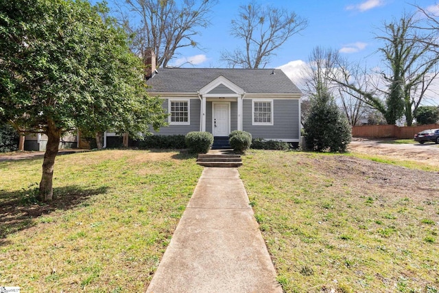 view of front of house with a front lawn, a chimney, and fence