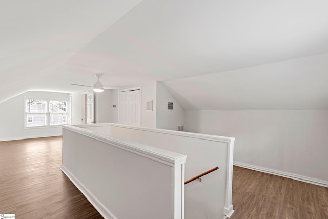 bonus room featuring baseboards, visible vents, vaulted ceiling, and wood finished floors