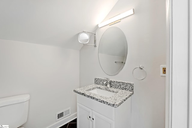 bathroom featuring baseboards, visible vents, lofted ceiling, toilet, and vanity