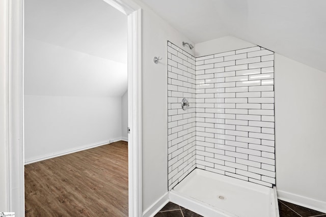 bathroom featuring lofted ceiling, wood finished floors, a shower stall, and baseboards