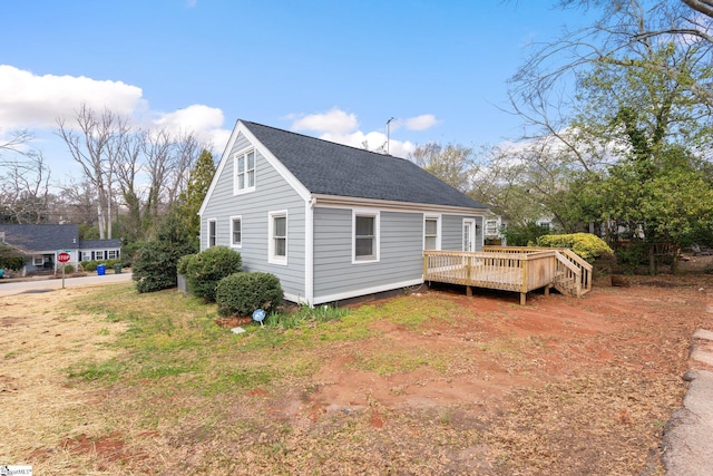 view of property exterior with a shingled roof and a deck