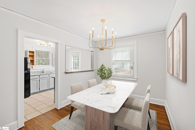 dining room with wood finished floors, crown molding, baseboards, and an inviting chandelier