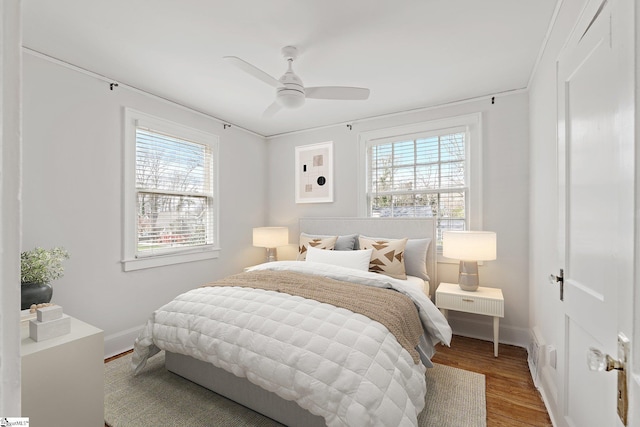 bedroom featuring multiple windows, wood finished floors, and baseboards