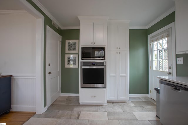 kitchen with appliances with stainless steel finishes, white cabinets, light countertops, and ornamental molding