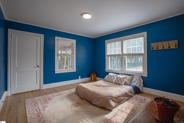 bedroom featuring multiple windows, ornamental molding, and wood finished floors