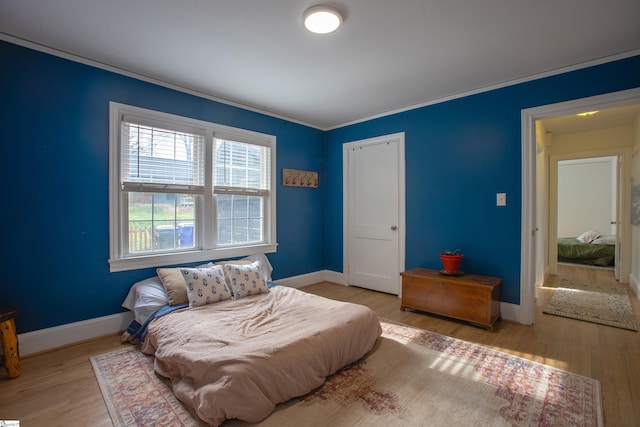 bedroom with ornamental molding, wood finished floors, and baseboards