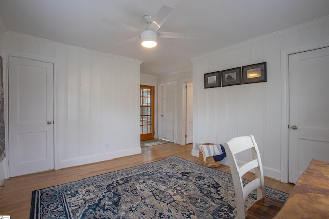 interior space featuring a ceiling fan, baseboards, ornamental molding, and wood finished floors