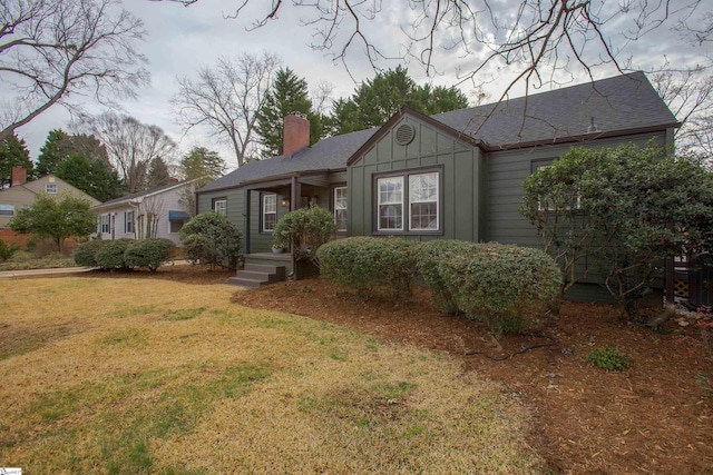 view of front of home with a front lawn, board and batten siding, and a chimney