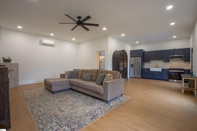 living area with ceiling fan, a wall mounted AC, light wood-type flooring, and recessed lighting