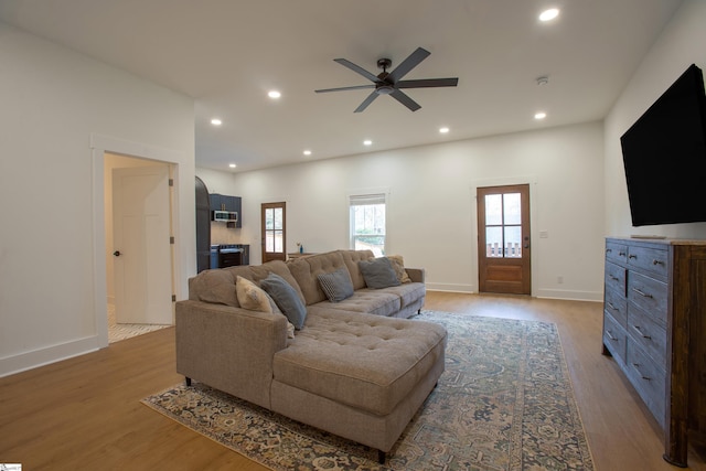 living area with light wood-type flooring, baseboards, a ceiling fan, and recessed lighting