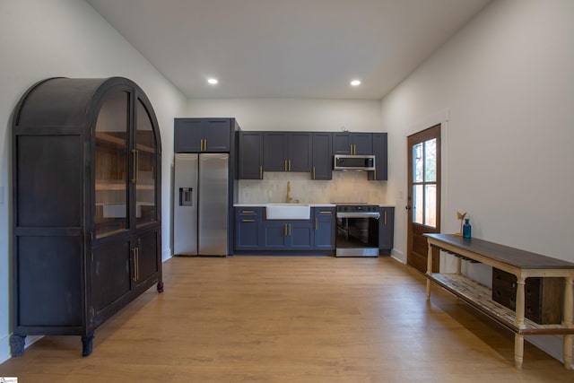 kitchen with stainless steel appliances, light countertops, a sink, and light wood finished floors