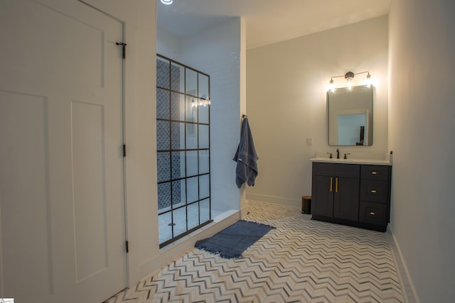 bathroom with tiled shower, vanity, and baseboards