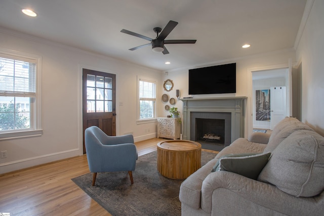 living room with a fireplace with flush hearth, baseboards, wood finished floors, and crown molding