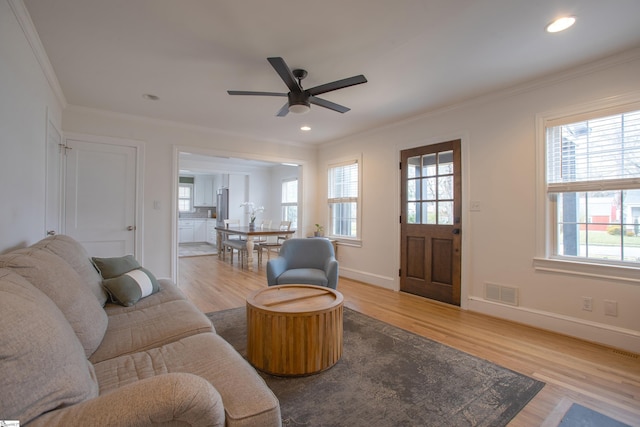 living area featuring ornamental molding, visible vents, and wood finished floors