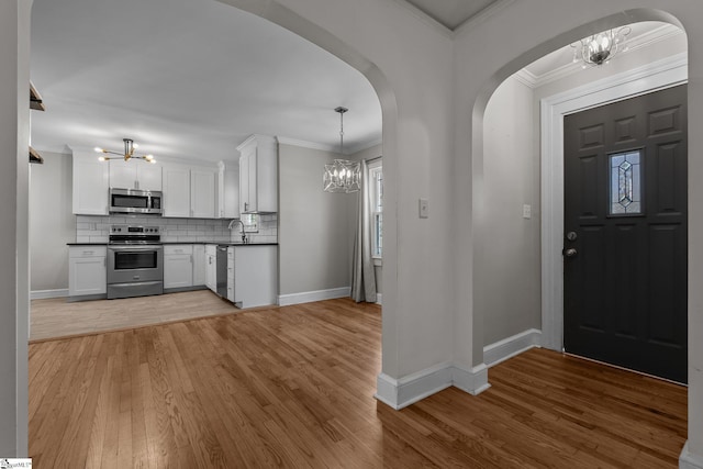 interior space featuring ornamental molding, light wood-style flooring, and a notable chandelier