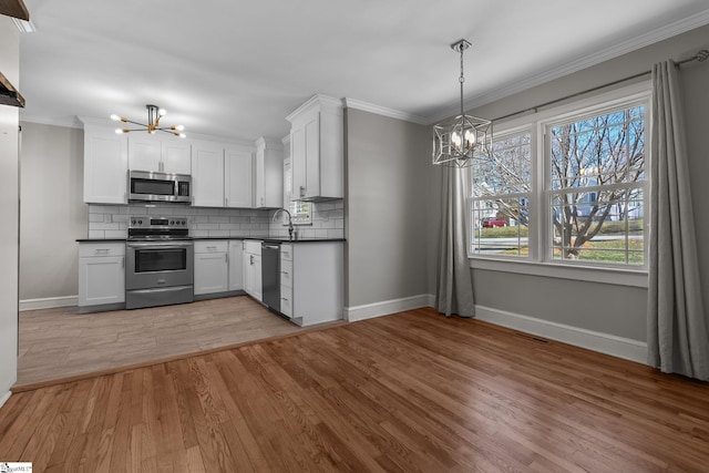 kitchen featuring appliances with stainless steel finishes, dark countertops, and a notable chandelier