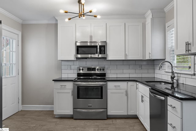 kitchen with a sink, ornamental molding, appliances with stainless steel finishes, tasteful backsplash, and dark countertops