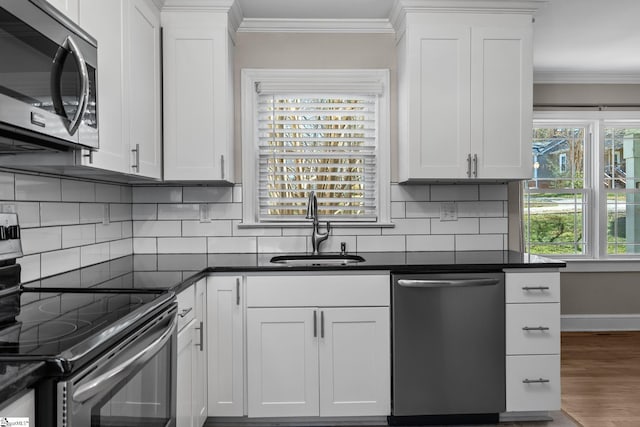 kitchen featuring appliances with stainless steel finishes, dark countertops, a sink, and ornamental molding