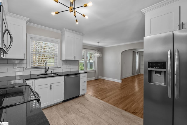 kitchen with tasteful backsplash, dark countertops, stainless steel appliances, a chandelier, and a sink