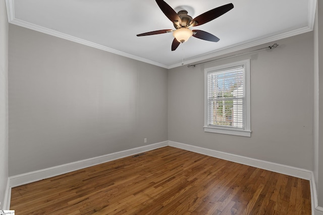 spare room featuring ceiling fan, wood finished floors, visible vents, baseboards, and crown molding