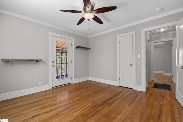 interior space featuring ceiling fan, ornamental molding, wood finished floors, and baseboards