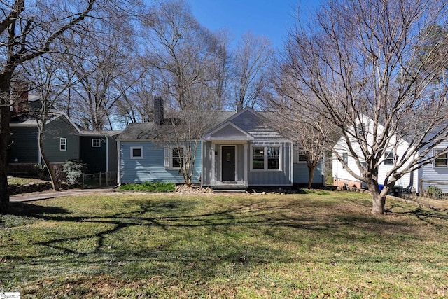 view of front of property featuring board and batten siding, a front yard, and a chimney